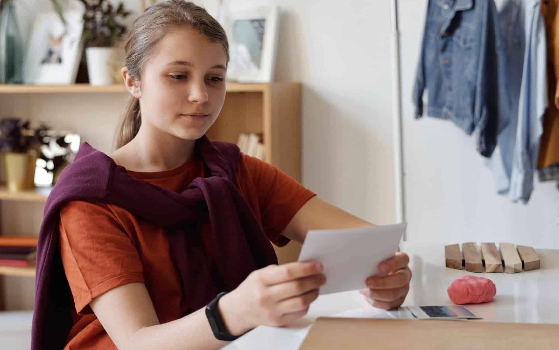 Uma garota branca observando uma folha de papel.