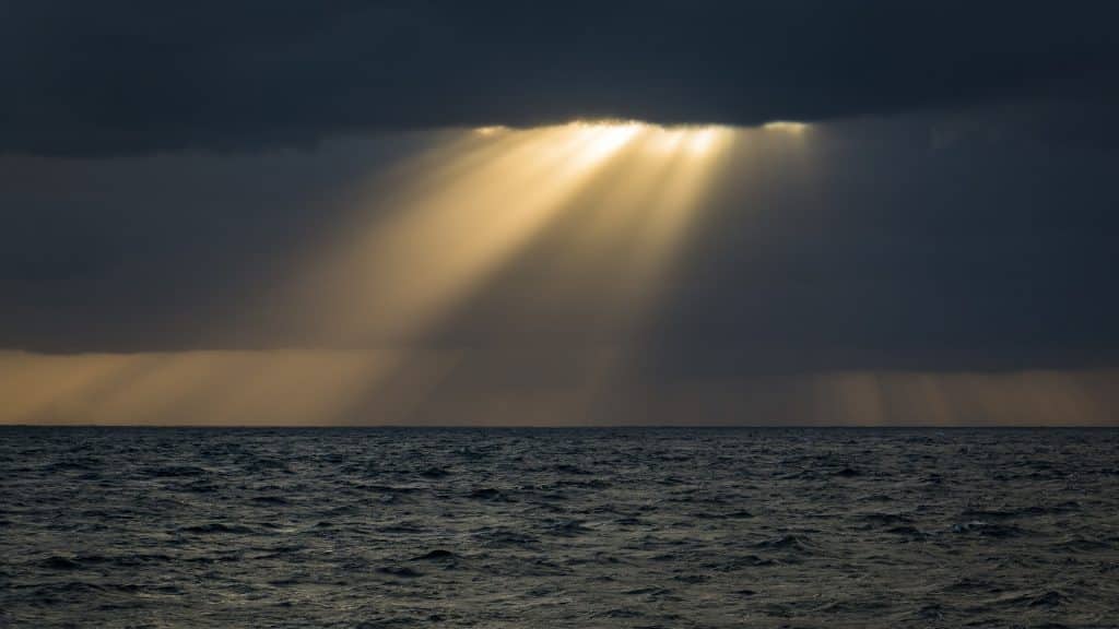 Um mar sendo iluminado por uma forte fresta de luz solar.