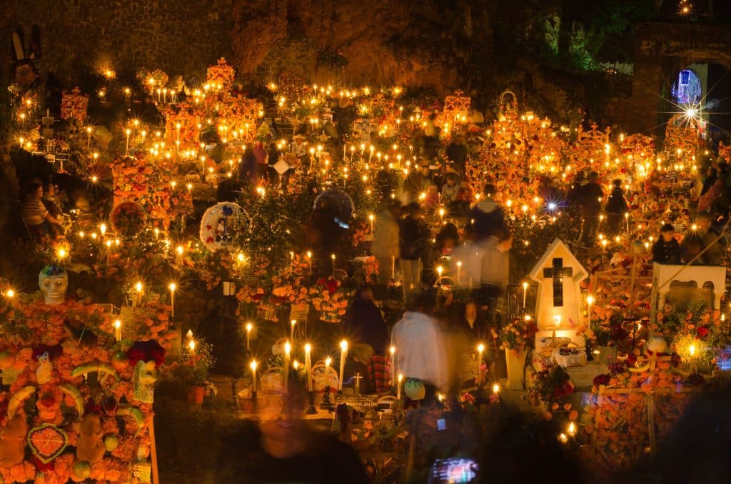 Noite dos Mortos em Janitzo. Várias pequenas velas dispersas, algumas lápides e plástico e algumas caveiras, todas também dispersas.