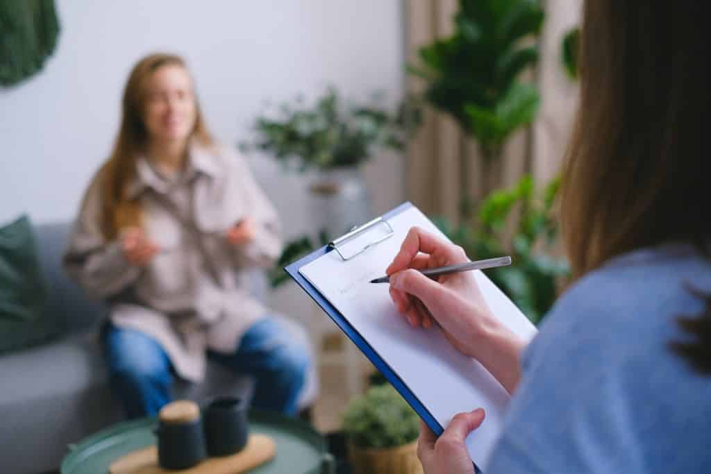 Duas mulheres conversando. Uma delas está fazendo anotações em uma prancheta.