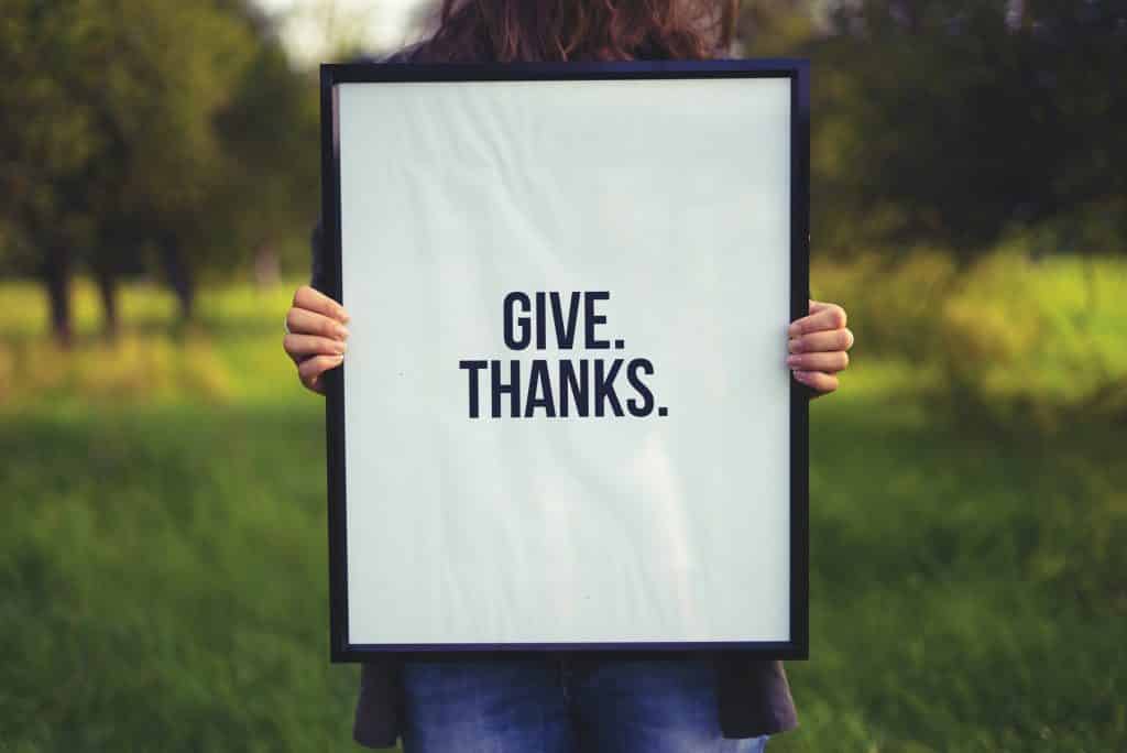 Uma pessoa segura um quadro escrito "give. thanks."