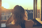 Uma mulher olhando um raio de sol pela janela.