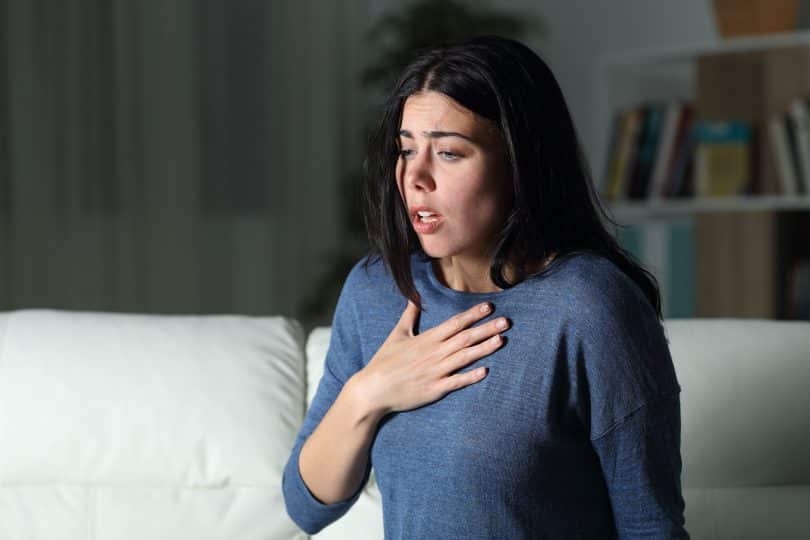 Uma mulher branca com uma blusa azul. Ela está sem ar.