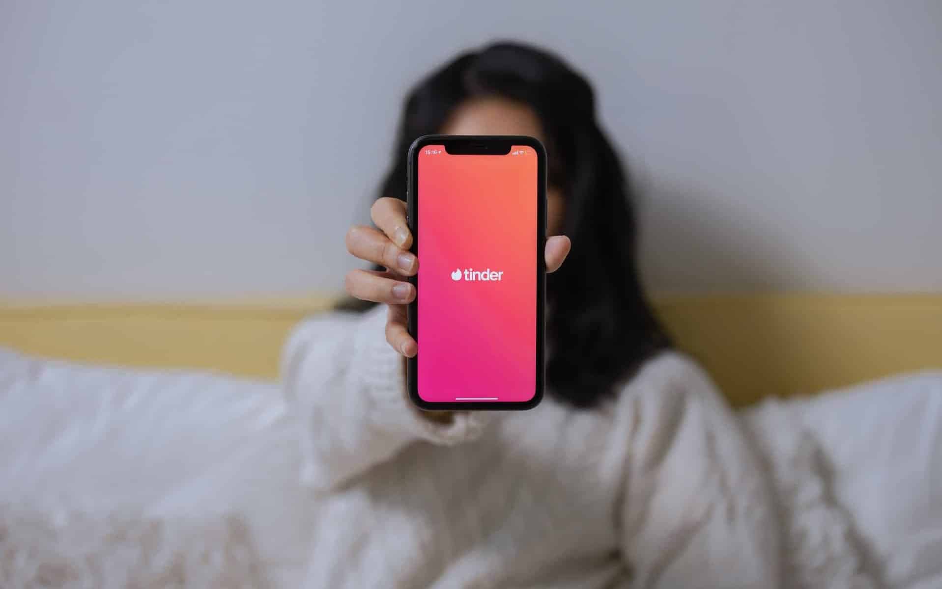 Uma pessoa segurando um celular com a aplicação Tinder sendo exibida na tela.