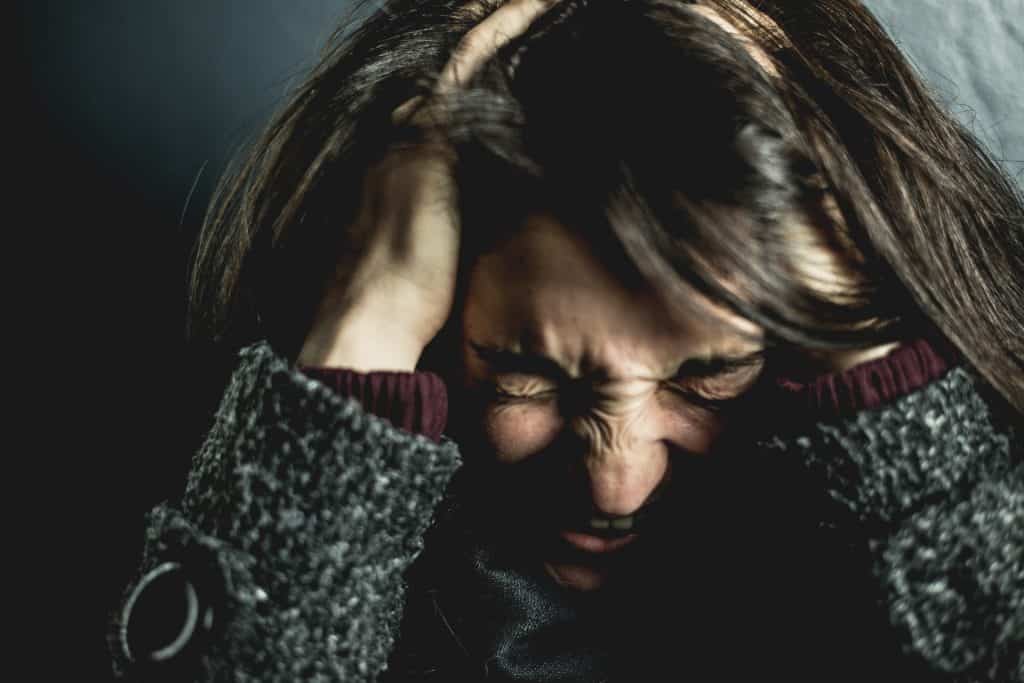 Uma mulher com as mãos na cabeça realizando uma expressão de estresse.