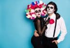 Um homem e uma mulher abraçados e fantasiados com trajes típicos do Día de Los Muertos Mexicano