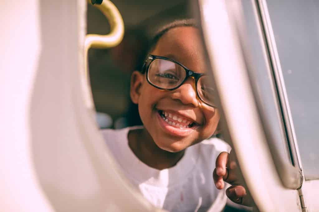 Menino negro de óculos sorrindo.