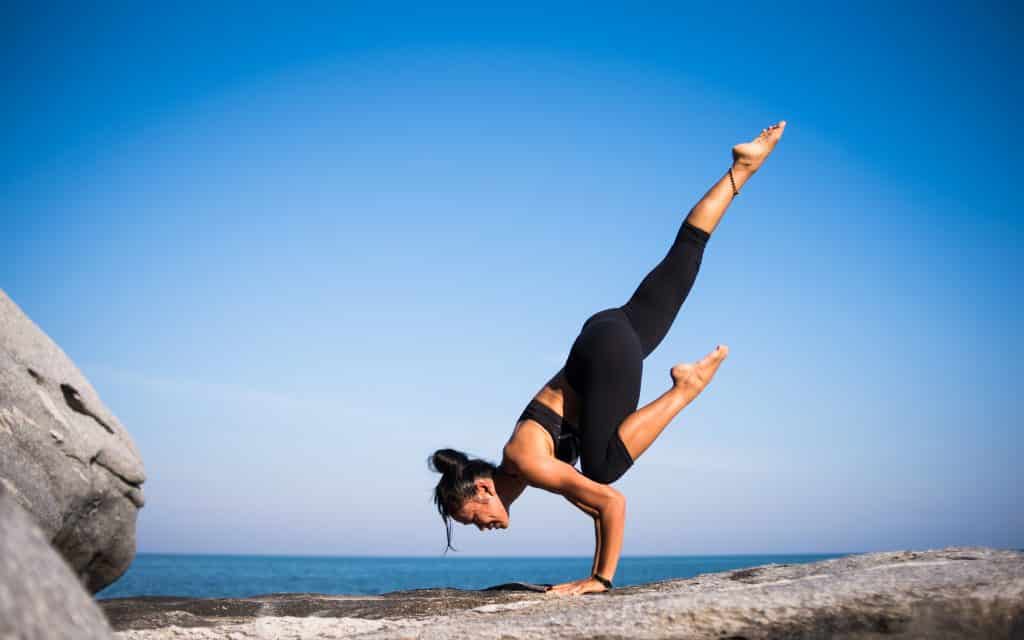 Mulher praticando yoga na praia