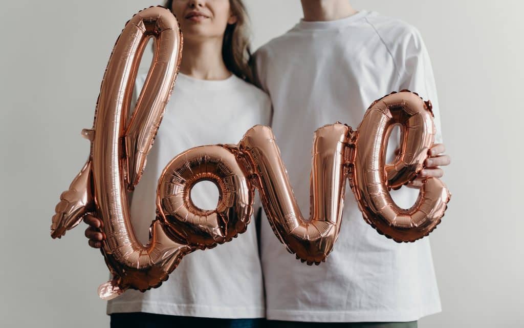 Casal segurando balão escrito "love"
