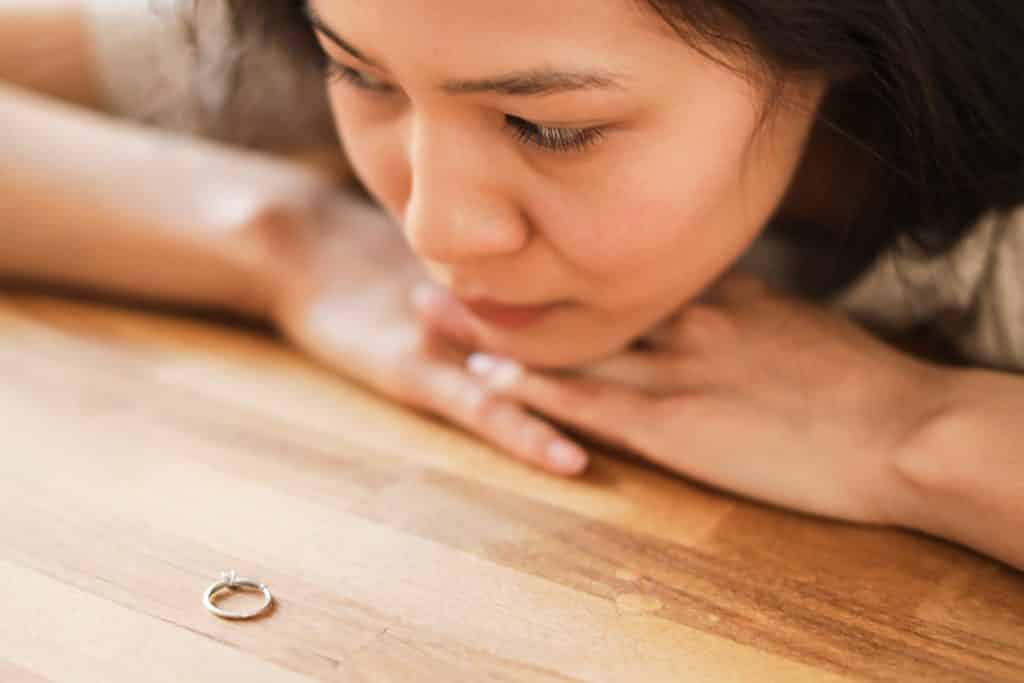 Mulher olhando para aliança na mesa