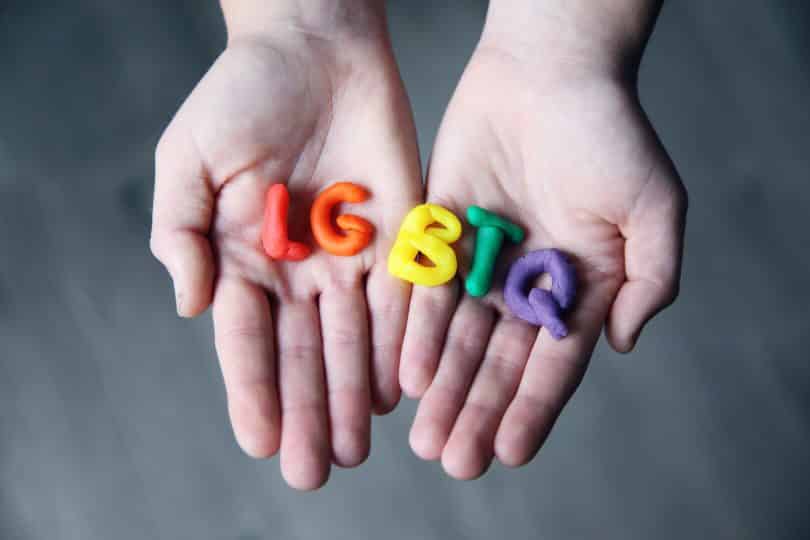 Mãos segurando letras feitas de massinha formando a sigla LGBT