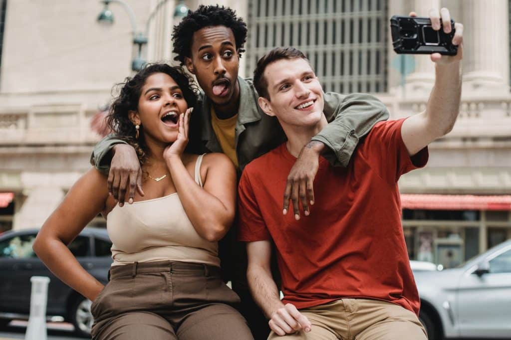 Dois homens e uma mulher tirando foto.