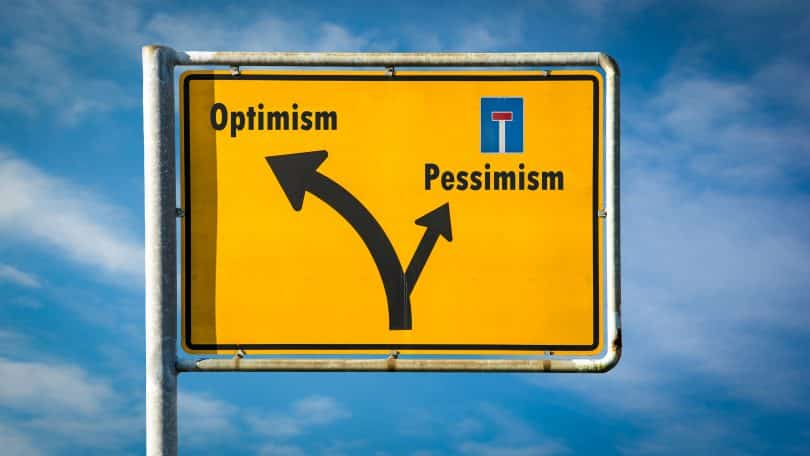 Uma placa com os seguintes elementos gráfico-visuais: 'pessimism' à esquerda, com uma seta à esquerda; com uma seta à direita, 'otimism'.