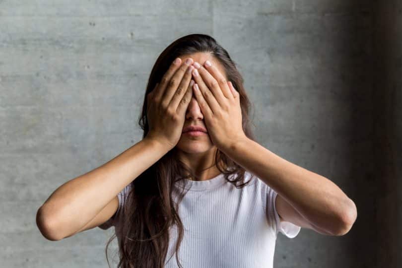 Mulher tapando os olhos com as duas mãos