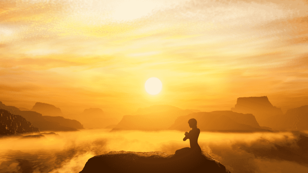Silhueta de uma pessoa meditando  no topo de uma montanha. O sol está em destaque no fundo