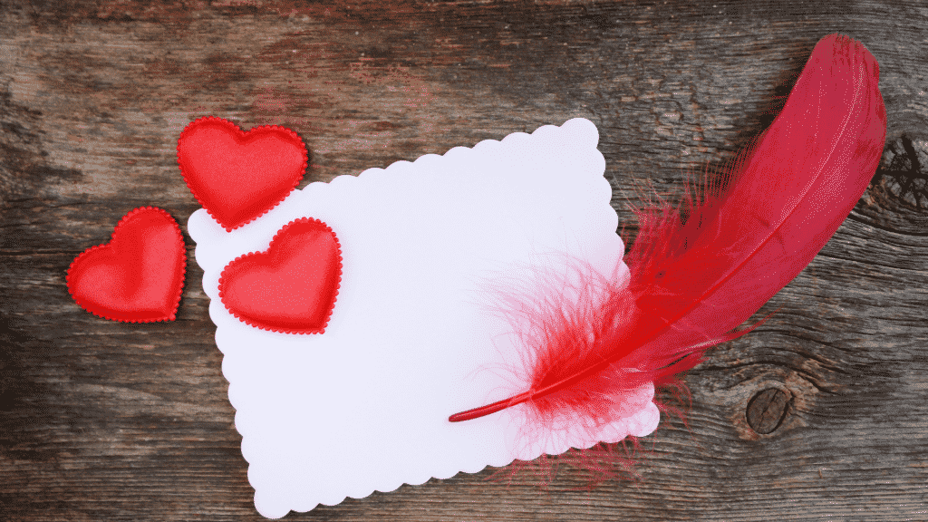 Bilhete romântico com corações e pena vermelha ao lado