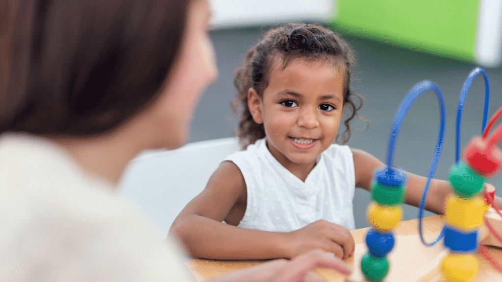 Menina sentada e sorrindo durante terapia infantil