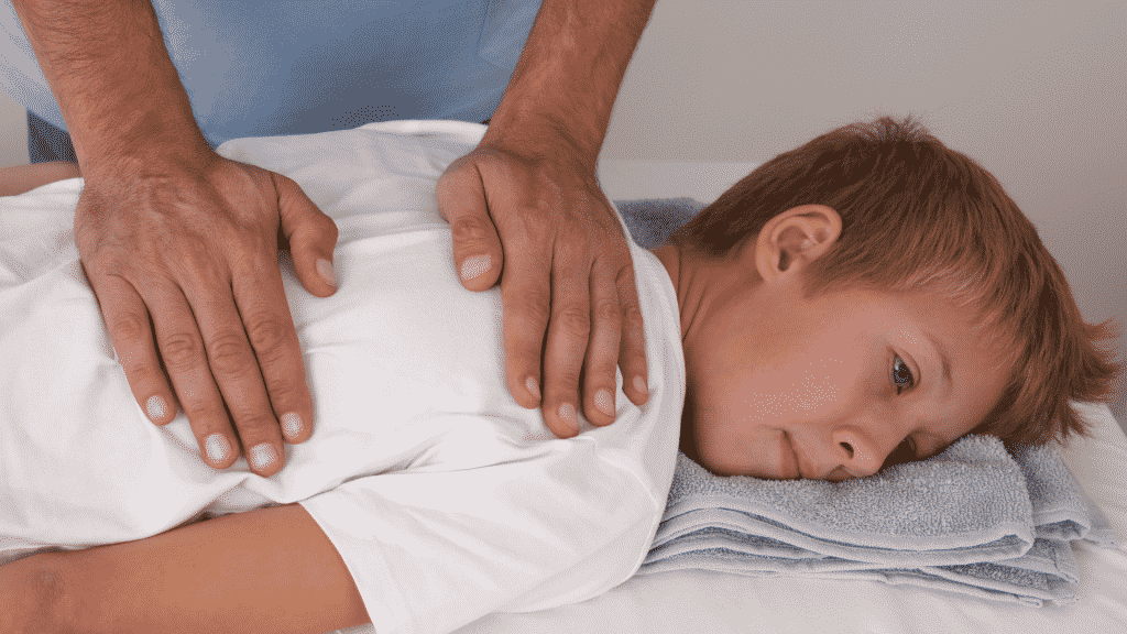 Menino deitado enquanto recebe uma massagem de terapeuta