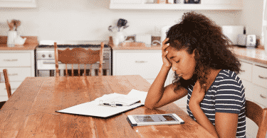 Menina estudando com expressão triste, uma mão na cabeça e a outra no peito