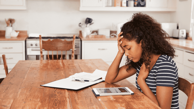 Menina estudando com expressão triste, uma mão na cabeça e a outra no peito