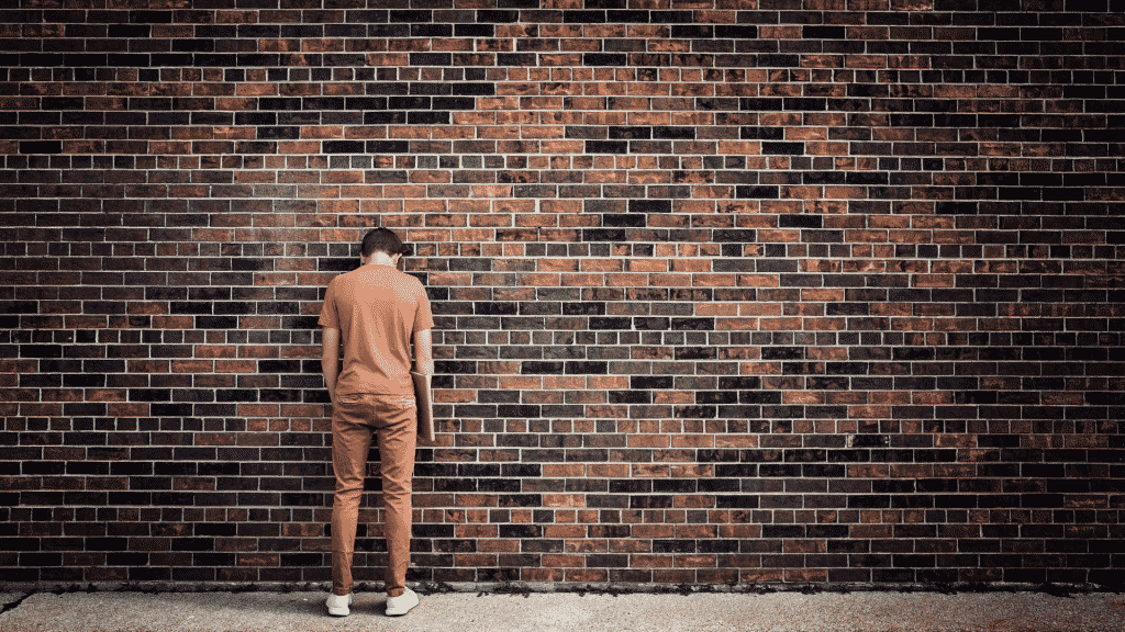 Homem com a cabeça encostada na parede.