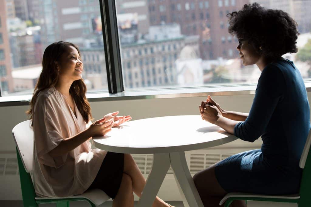 Duas mulheres conversando sentadas à mesa.