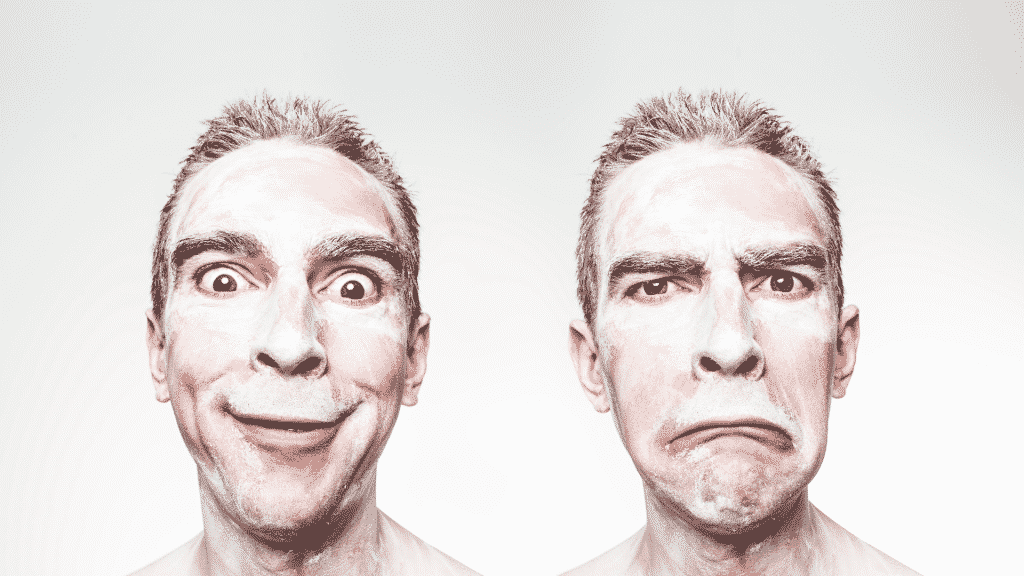 Um homem exibindo, concomitantemente (lado a lado), uma expressão de felicidade e outra aborrecimento. Ambas são caricaturizadas. 