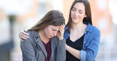 Uma mulher à esquerda consolando outra mulher à direita.