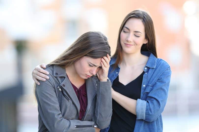 Uma mulher à esquerda consolando outra mulher à direita.