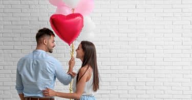 Um homem e uma mulher segurando balões em formato de coração.