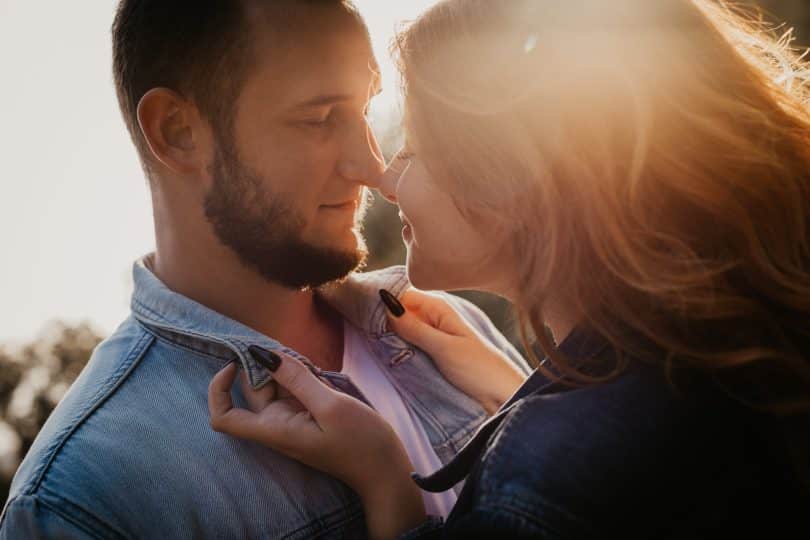Um homem e uma mulher se abraçando. Eles tocam ambos seus narizes.