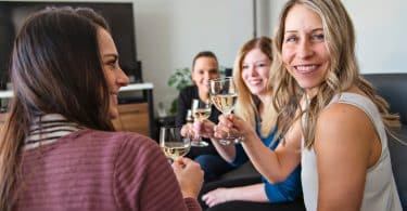 Mulheres em uma sala, brindando taças e conversando.