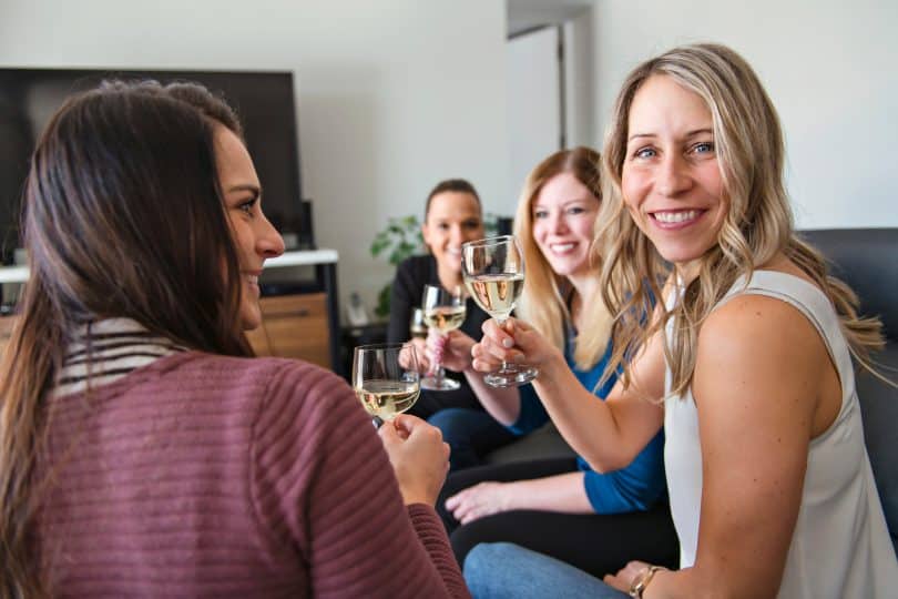 Mulheres em uma sala, brindando taças e conversando.