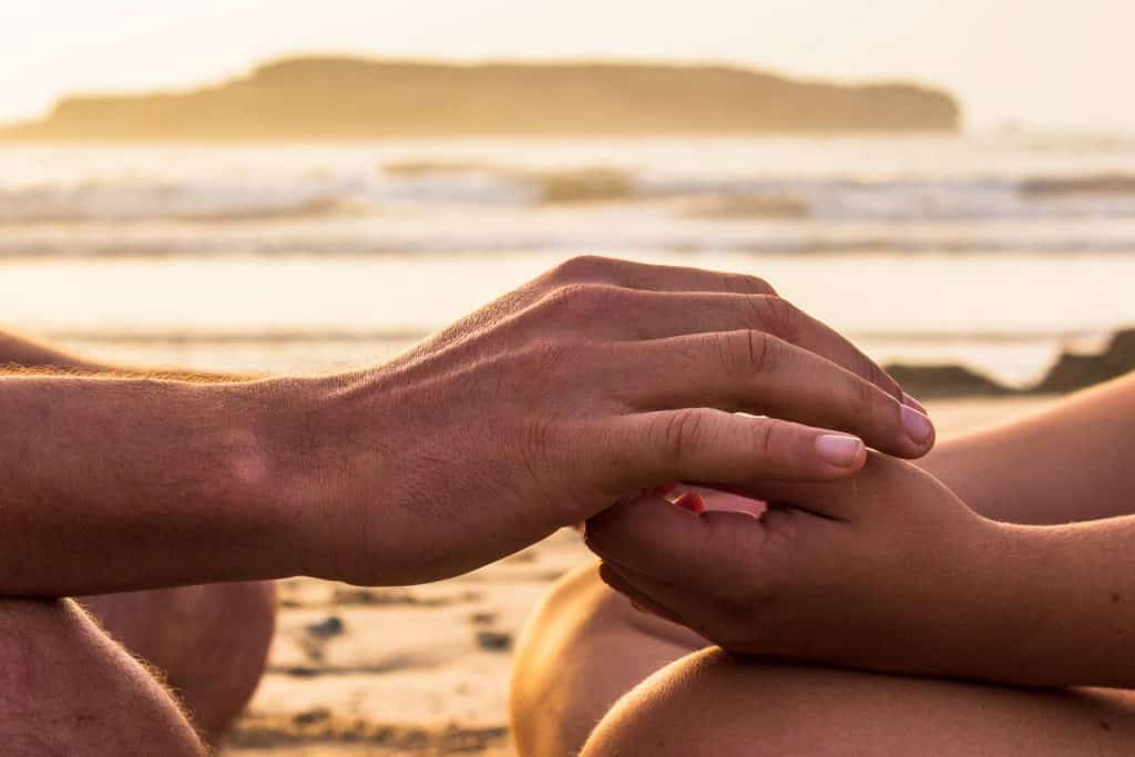 Mãos juntas numa praia.