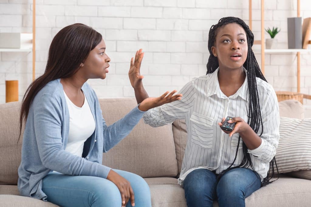 Uma mulher argumenta, à esquerda, enquanto outra, à direita, nega-se ouvi-la. 