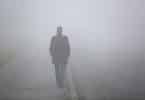 Um homem andando em meio à névoa.