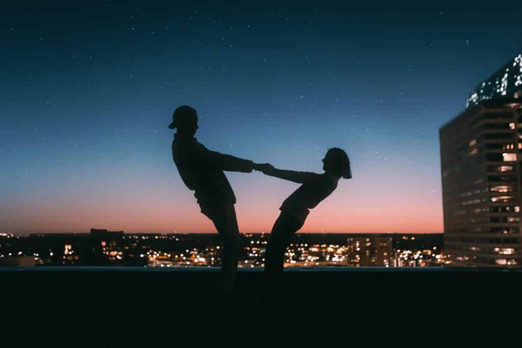 Dois amigos de mãos dadas em frente ao pôr do Sol