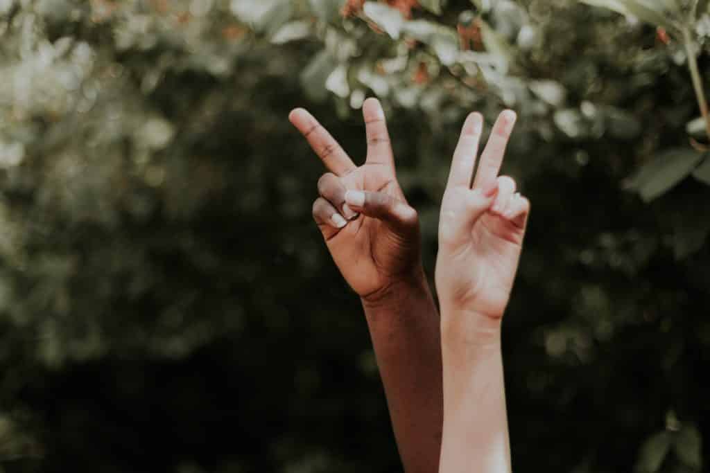 Mãos negra e branca com os dedos levantados.