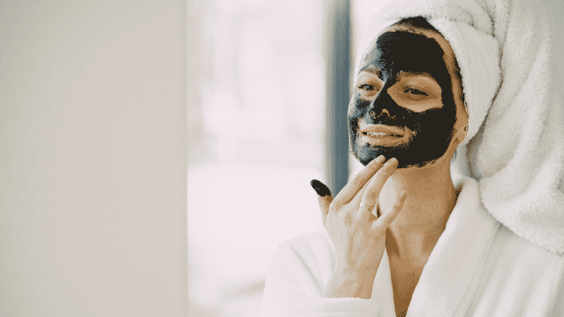 Mulher fazendo skin care com máscara de carvão