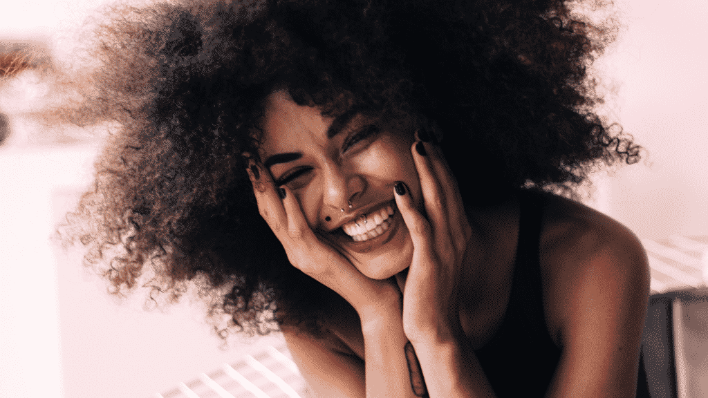 Mulher sorrindo com as mãos no rosto