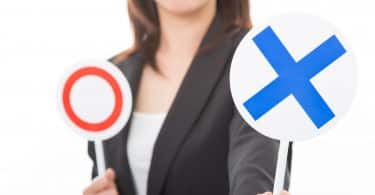 Uma mulher erguendo uma placa com um X azul. A outra placa, retida, é um círculo vermelho.