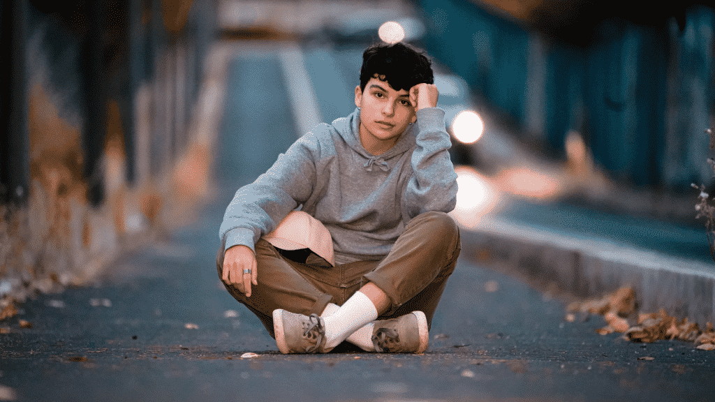 Menino adolescente sentado no chão em uma rua vazia