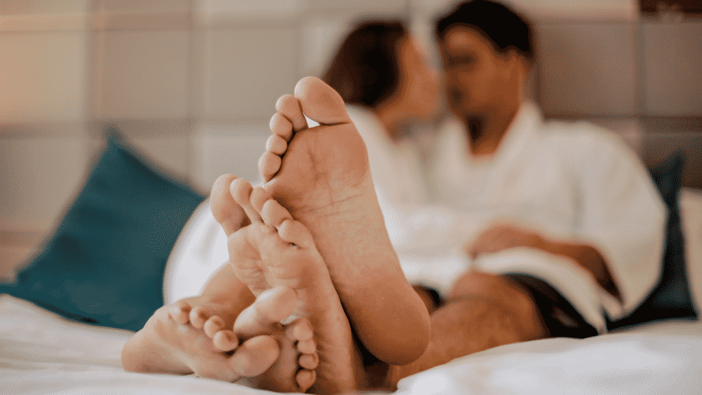 Imagem com o foco nos pés de um casal deitado na cama