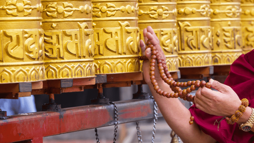 Pessoa segurando um japamala e tocando em escritas douradas de um templo