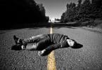 Um homem supostamente morto com o corpo deitado sobre uma estrada.
