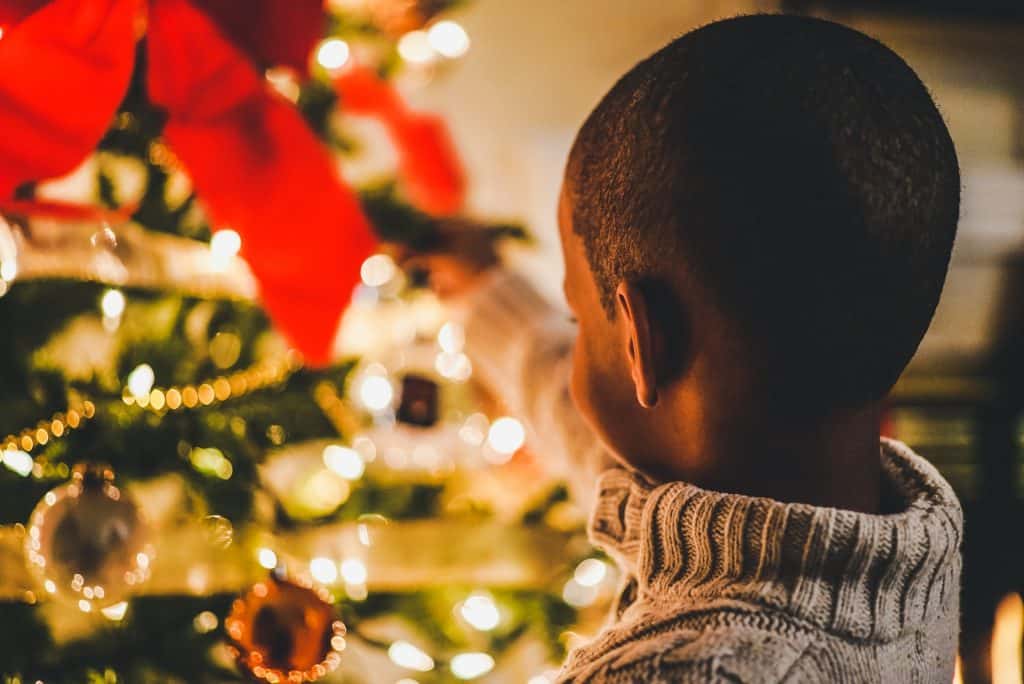 Menino negro olhando árvore de natal.