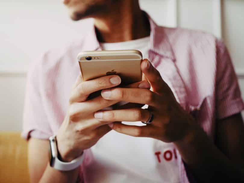 Homem negro segurando celular.