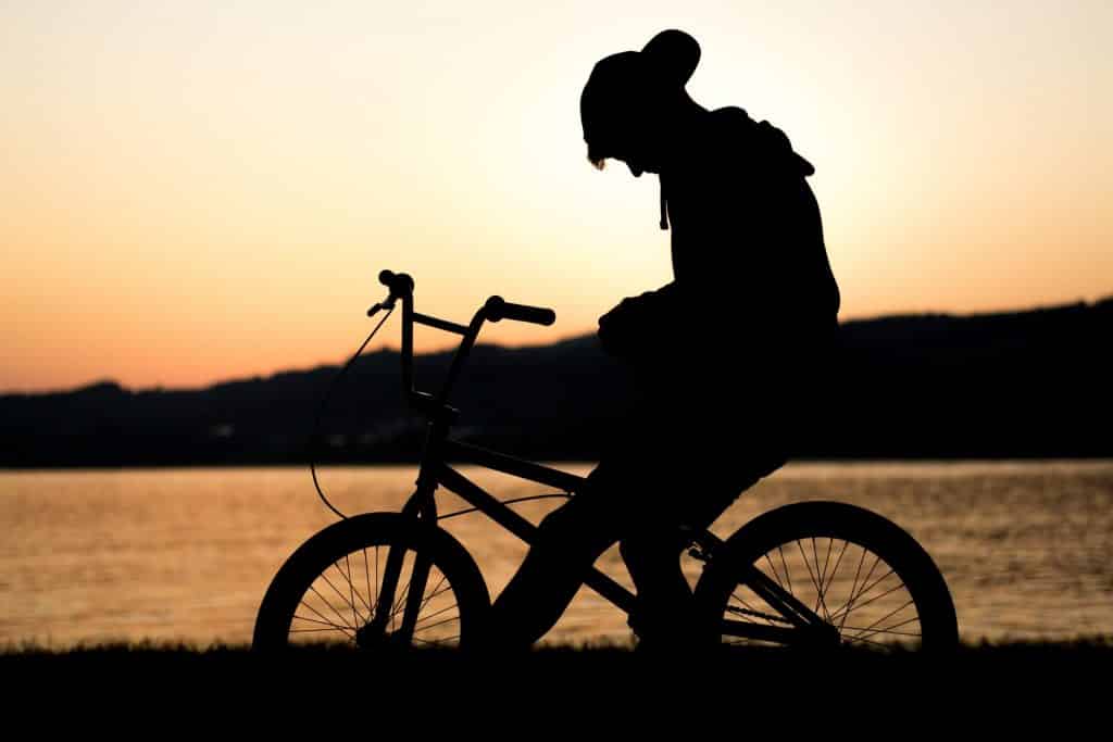 Silhueta de menino numa bicicleta.