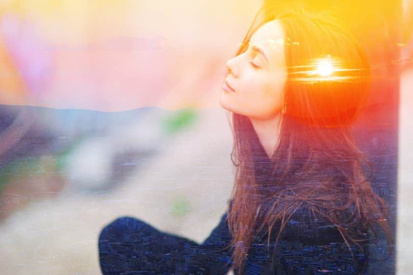 Mulher meditando ao ar livre com os olhos fechados