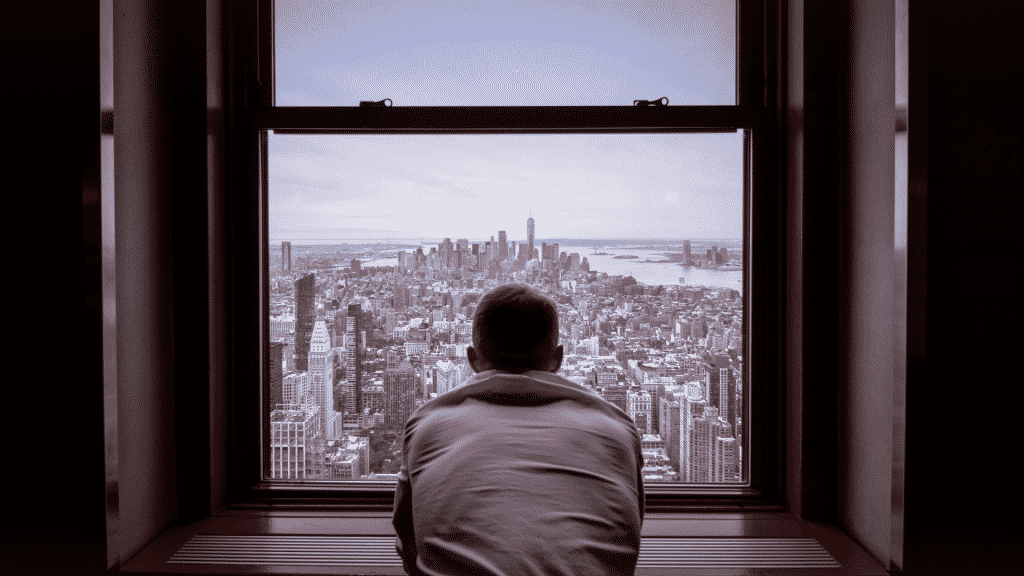 Homem olhando pensativo pela janela
